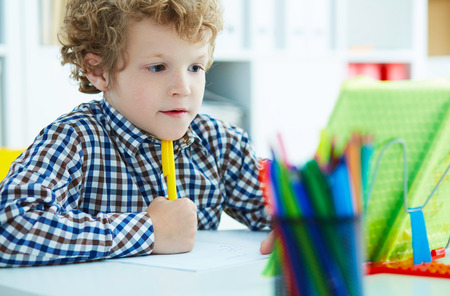 Portrait of pupil in school class taking notes during writing lesson. Education, childhood, people, homework and school concept.の写真素材