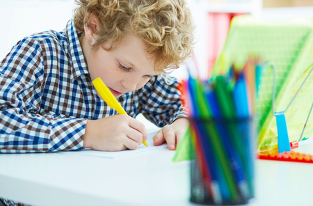 Portrait of pupil in school class taking notes during writing lesson. Education, childhood, homework and school concept.の写真素材