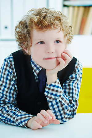 Elementary schoolboy thinking while doing homework in classroom, into the distance.の写真素材