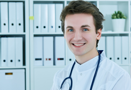 Portrait of young male doctor with stethoscope, close up. Young therapist or a pediatrician is ready to receive a patient.の写真素材