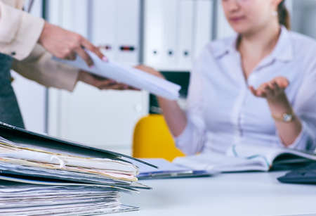 Paperwork - human hand holding business paper files. Lot of work wait for tired and exhausted woman.の写真素材