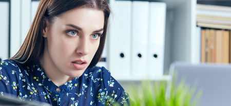 Portrait of young serious businesswoman using laptop in office.の写真素材