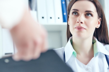 Beautiful smiling female medicine doctor listening carefully patient complaints in medical office. Medical care or insurance concept.の写真素材