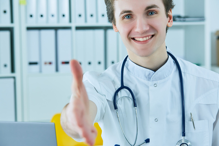Male medicine doctor offering hand for handshake. Partnership and trust concept.の写真素材
