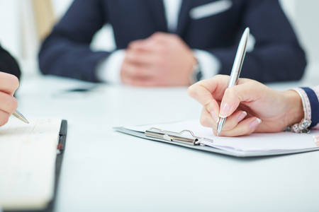 Female hands holding a silver pen closeup. Business job offer, financial success, certified public accountant concept.の写真素材