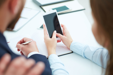Young businesswoman showin phone screen to colleagues in office.の写真素材