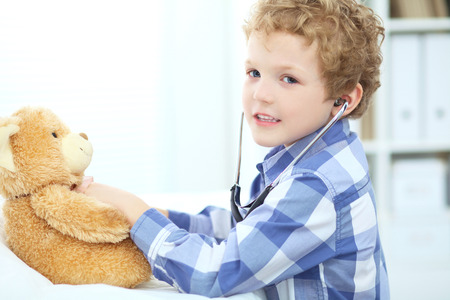 Little boy plays in doctor with Teddy Bear and stethoscope.の写真素材