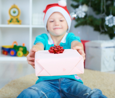 Happy boy in red christmas hat with christmas present box. Selective focus.の写真素材