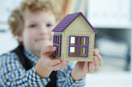 The childs hand holds the house. Family, purchase of housing, apartment, mortgage, inheritance.の写真素材