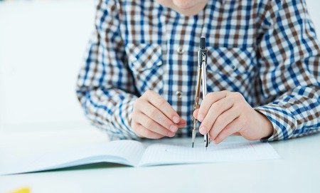 Little boy using engineer divider compass to measure the distance on paper.の写真素材