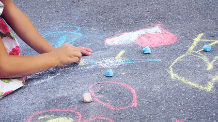 The child drawing a chalk on asphalt. Child drawings paintings on asphalt concept.の写真素材