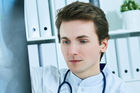 Close up portrait of young male doctor holding x-ray or roentgen image.の写真素材