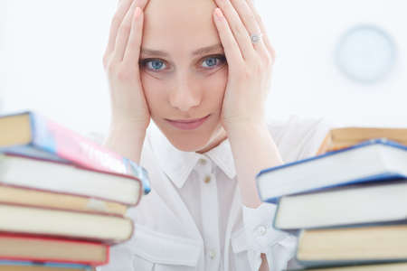 Sad female student working in library.