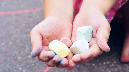 Chalk in childs hands close-up. The child drawing a chalk on asphalt. Child drawings paintings on asphalt concept.の写真素材