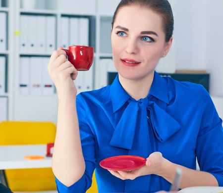Female office workers sitting at the table and speaking and drinking coffee.の写真素材