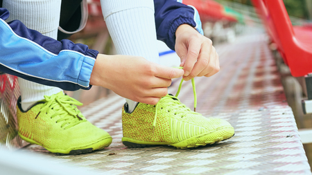Boy football soccer tying the laces on the boots on grassy football stadium.の写真素材