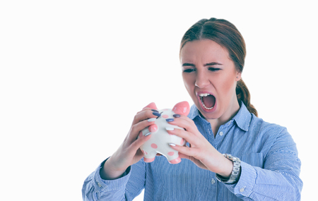 Woman is aggressively yelling at piggy bank. Isolated over white background.の写真素材