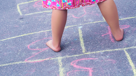 Closeup of little boys legs and hopscotch drawn on asphalt. Child playing hopscotch game on playground outdoors.の写真素材