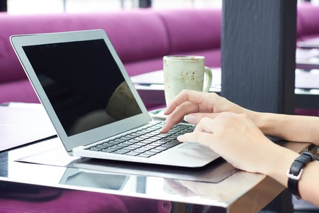 Cropped view of young female office worker sitting at table in cafe enjoying coffee and surfing internet after hard day at work.の写真素材