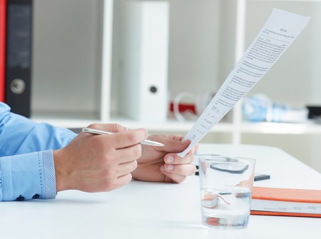 Cropped image of businessmans hands holding document and silver pen.の写真素材