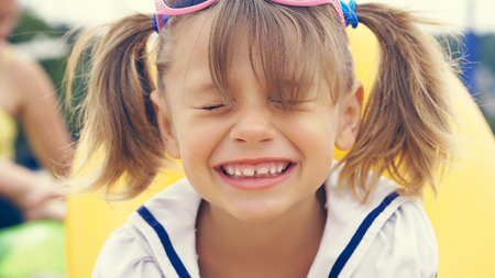 Outdoor portrait of cute small girl sitting on beach sand. Summer sunny day. Happy holidays on the...