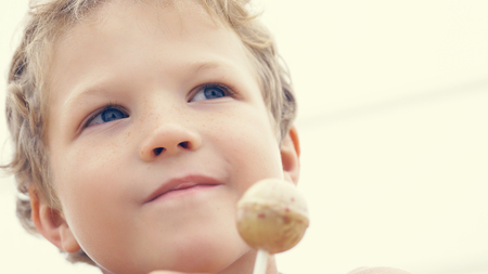 Happy little preschool boy with candy lollypop at summer beach, outdoors.の写真素材