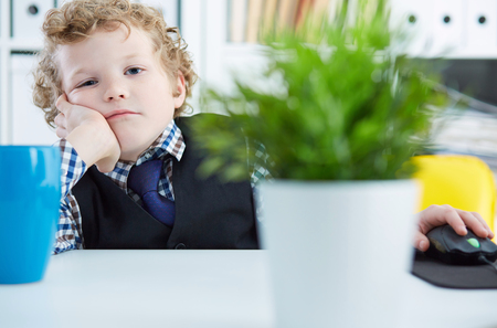 Portrait of tired business child wearing formal shirt and tie. Cute little boy covering his mouth with hands, imitating office worker or businessperson.の写真素材