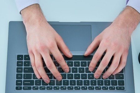 Male hands typing on laptop keyboard. Young man using laptop computer. Business working concept.の写真素材