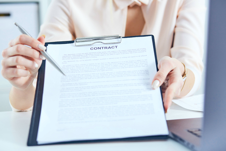 Young businesswoman giving contract for you to sign. Just Hands over the table.の写真素材