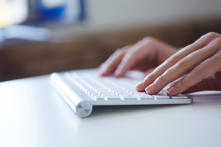 Closeup image of female hand typing on desktop computer keyboard.の写真素材
