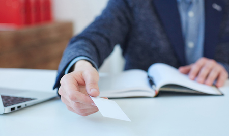 Man hand giving business card in office. Man showing blank business card. Mock up design.の写真素材