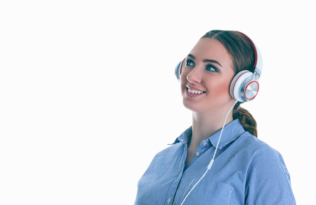 Beautiful woman with headphones daydreaming - isolated over white background.の写真素材