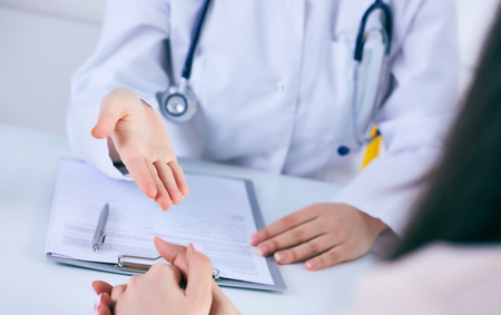 Female doctor giving a consultation to a patient and explaining medical informations and diagnosis. Just hands over the table.の写真素材