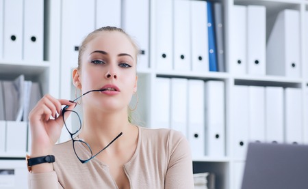 Sexy secretary with glasses in hand undresses in office, flirt and desire. Office provocation.の写真素材