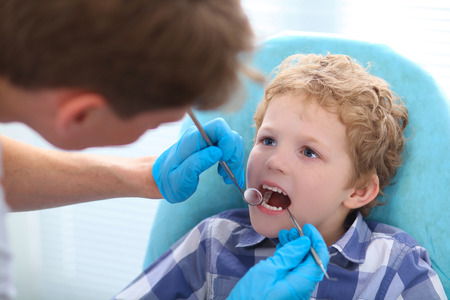 Close up portrait of boy having his teeth examined by a dentist.の写真素材