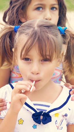 Cute sisters enjoying lollipops outside at the Beach.の写真素材