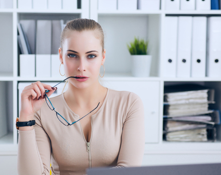 Sexy secretary with glasses in hand undresses in office, flirt and desire. Office provocation.の写真素材