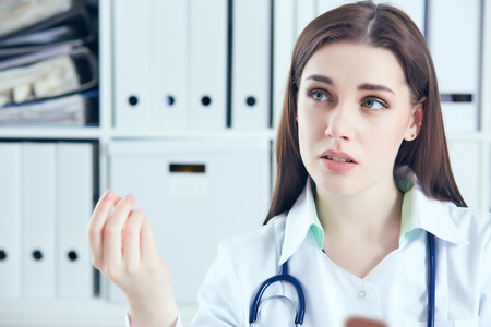 Young female doctor giving a consultation to a patient and explaining medical informations and diagnosisの写真素材