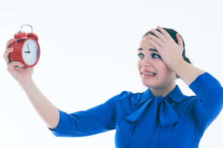 Portrait of shocked and angry woman with alarm clock over white background.の写真素材