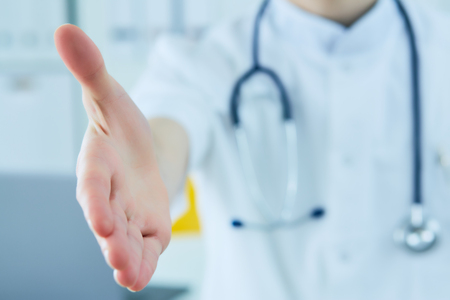 Male medicine doctor offering hand for handshake close up. Partnership and trust concept.の写真素材