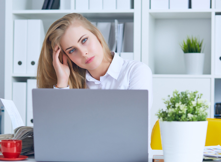 Tired Caucasian businesswoman massaging head. Exhausted female office worker gather herself for completing workの写真素材