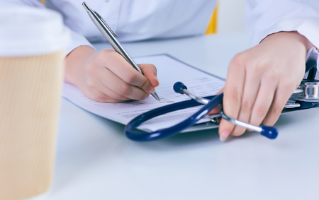 Close up of a female doctor filling up an application form while consulting patient. Medicine and health care conceptの写真素材