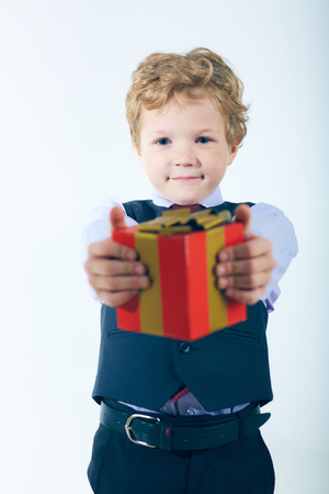 Little smiling boy giving a gift to someone. Gifts on holidaysの写真素材