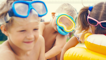 Portrait of the happy children with swimming mask on head playing onthe sea beach.の写真素材