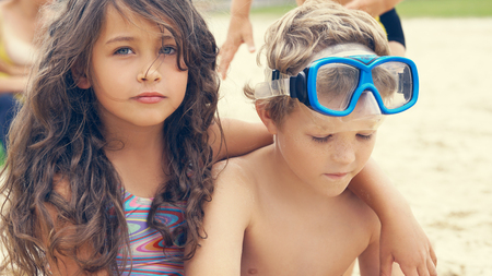 Portrait of children on the beach in summer. Little girl hugs her brother and smiling.の写真素材