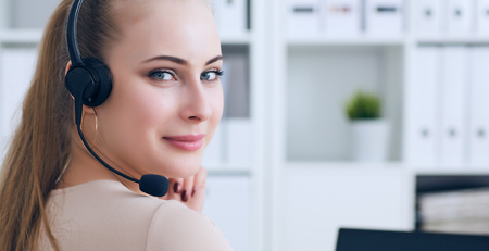 Portrait of happy smiling female customer support phone operator at workplace.の写真素材