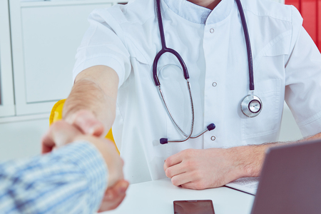 Close up of a male doctor shaking hands with his male patient. Medicine and trust conceptの写真素材