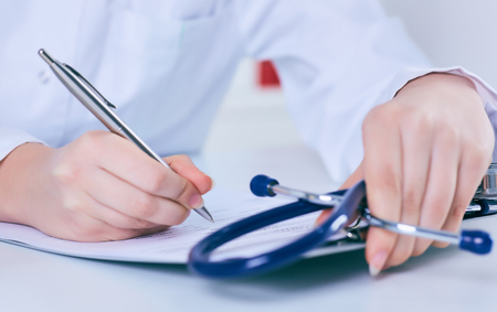 Close up of a female doctor filling up an application form while consulting patient. Medicine and health care conceptの写真素材