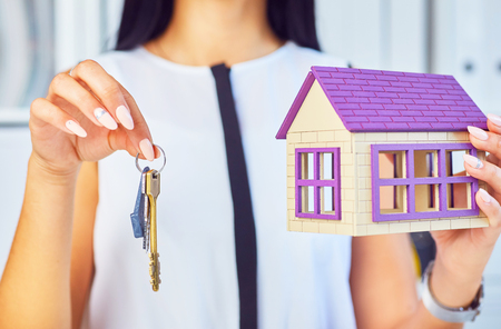 Young businesswoman or real estate agent with hose model and keys in hands closeup.の写真素材