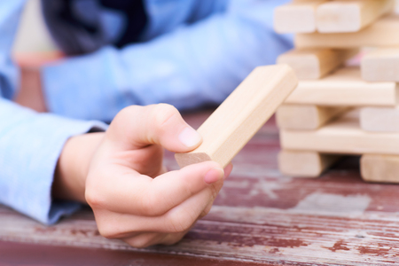 Close up kids hand playing wood blocks tower game for practicing physical and mental skill.の写真素材
